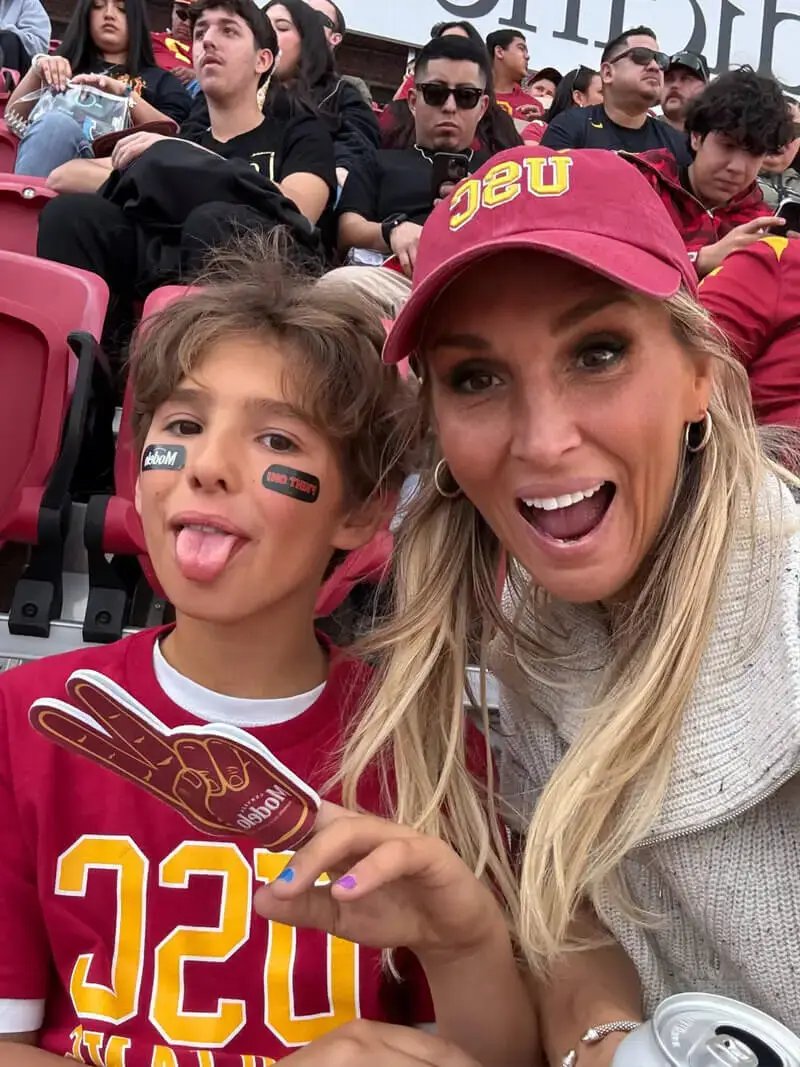 Judith Fetzer et un jeune garçon en t-shirts USC assistant à un match dans les gradins, souriants et enthousiastes parmi la foule