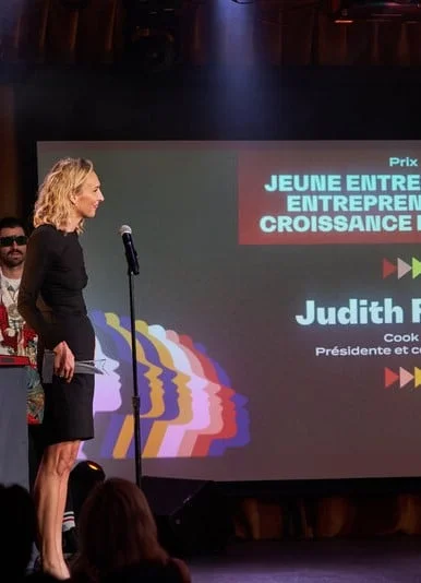 Judith Fetzer sur scène recevant un prix lors d'un gala, devant un écran affichant “Jeune entreprise en croissance” et son nom en tant que présidente et cofondatrice de Cook it