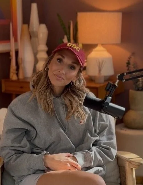 Judith Fetzer assise dans un fauteuil devant un micro de podcast, portant un chandail gris et une casquette bourgogne avec le logo USC, dans un décor chaleureux aux tons boisés
